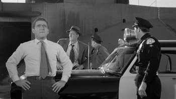 Movie still from “Them!” (1954), directed by Gordon Douglas – A black - and - white photo of men in suits and hats in front of a police car; Medium shot, Low angle