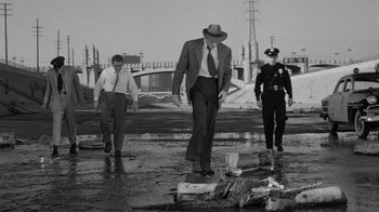 Movie still from “Them!” (1954), directed by Gordon Douglas – A man in a suit and tie walking across a street; Wide shot, High angle