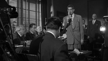 Movie still from “Them!” (1954), directed by Gordon Douglas – An old photo of a man speaking at a meeting; Medium shot, Low angle