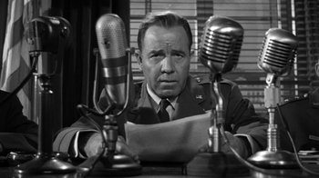 Movie still from “Them!” (1954), directed by Gordon Douglas – An old photo of a man in a military uniform with two microphones in front of him; Close Up shot, Low angle