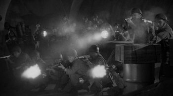 Movie still from “Them!” (1954), directed by Gordon Douglas – A group of men in uniforms are holding guns; Wide shot, High angle