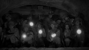 Movie still from “Them!” (1954), directed by Gordon Douglas – A group of men in a cave holding flashlights; Wide shot, High angle
