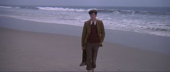 Movie still from “They Shoot Horses, Don't They?” (1969), directed by Sydney Pollack – A man standing on the beach holding a surfboard; Wide shot, Low angle