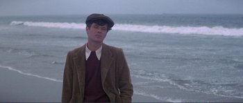 Movie still from “They Shoot Horses, Don't They?” (1969), directed by Sydney Pollack – A man in a brown jacket standing in front of the ocean; Medium shot, High angle