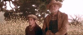 Movie still from “They Shoot Horses, Don't They?” (1969), directed by Sydney Pollack – A man and a boy standing next to each other in a field; Medium shot, Low angle