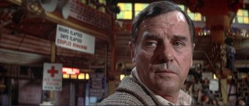 Movie still from “They Shoot Horses, Don't They?” (1969), directed by Sydney Pollack – An older man wearing a sweater in front of a building; Close Up shot, Low angle