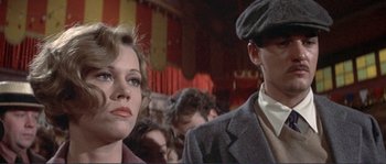 Movie still from “They Shoot Horses, Don't They?” (1969), directed by Sydney Pollack – A man and a woman are standing in front of a crowd; Close Up shot, Low angle