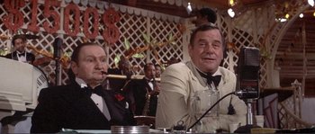 Movie still from “They Shoot Horses, Don't They?” (1969), directed by Sydney Pollack – Two men sitting at a table in front of a microphone; Medium shot, Over the shoulder angle