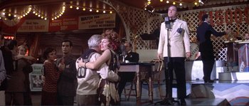 Movie still from “They Shoot Horses, Don't They?” (1969), directed by Sydney Pollack – A man and a woman hugging in front of a microphone; Wide shot, Low angle