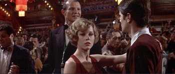 Movie still from “They Shoot Horses, Don't They?” (1969), directed by Sydney Pollack – A woman in a red dress sitting next to a man in a black suit; Medium shot, Over the shoulder angle