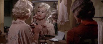 Movie still from “They Shoot Horses, Don't They?” (1969), directed by Sydney Pollack – A woman is looking in the mirror and putting lipstick on; Close Up shot, Over the shoulder angle