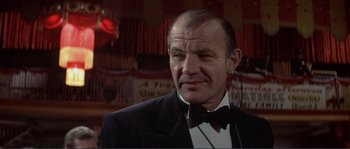 Movie still from “They Shoot Horses, Don't They?” (1969), directed by Sydney Pollack – An older man wearing a tuxedo in front of a red light; Close Up shot, Low angle