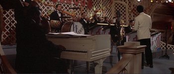 Movie still from “They Shoot Horses, Don't They?” (1969), directed by Sydney Pollack – A group of people playing musical instruments in front of a piano; Wide shot, High angle