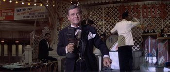 Movie still from “They Shoot Horses, Don't They?” (1969), directed by Sydney Pollack – An older man in a tuxedo holding a microphone; Medium shot, Low angle