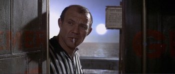 Movie still from “They Shoot Horses, Don't They?” (1969), directed by Sydney Pollack – A person smoking a cigarette near a street sign; Medium shot, Low angle