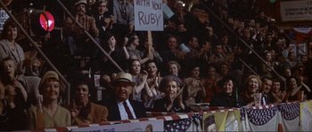 Movie still from “They Shoot Horses, Don't They?” (1969), directed by Sydney Pollack – A group of people sitting in front of an american flag; Medium shot, Over the shoulder angle