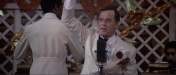 Movie still from “They Shoot Horses, Don't They?” (1969), directed by Sydney Pollack – A man in a white suit holding a microphone; Close Up shot, High angle