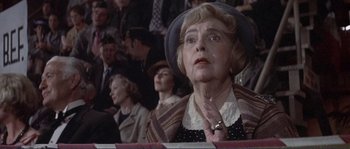 Movie still from “They Shoot Horses, Don't They?” (1969), directed by Sydney Pollack – An older woman in a crowd of people with her hands clasped together; Close Up shot, Over the shoulder angle