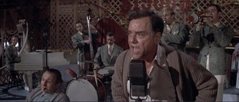Movie still from “They Shoot Horses, Don't They?” (1969), directed by Sydney Pollack – An older man is singing in front of a band; Medium shot, Low angle