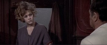 Movie still from “They Shoot Horses, Don't They?” (1969), directed by Sydney Pollack – A woman standing in front of a window in a dark room; Close Up shot, Over the shoulder angle