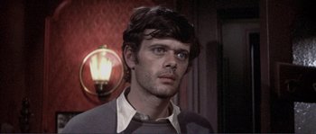 Movie still from “They Shoot Horses, Don't They?” (1969), directed by Sydney Pollack – A man with a beard is standing in front of a lamp; Close Up shot, High angle