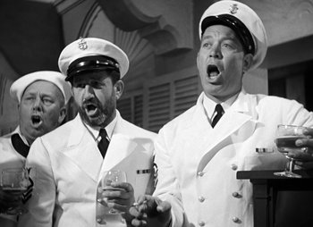 Movie still from “They Were Expendable” (1945), directed by Robert Montgomery – A black and white photo of two men in uniforms singing; Medium shot, Low angle