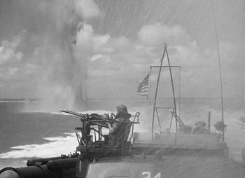 Movie still from “They Were Expendable” (1945), directed by Robert Montgomery – A soldier sitting on top of a boat in the water; Extreme Wide shot, Low angle
