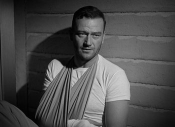Movie still from “They Were Expendable” (1945), directed by Robert Montgomery – A black and white photo of a man with a bandage on his arm; Medium shot, Low angle