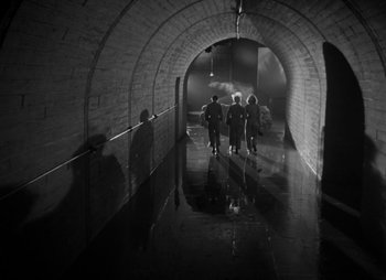 Movie still from “They Were Expendable” (1945), directed by Robert Montgomery – A group of people walking down a dark tunnel; Extreme Wide shot, High angle