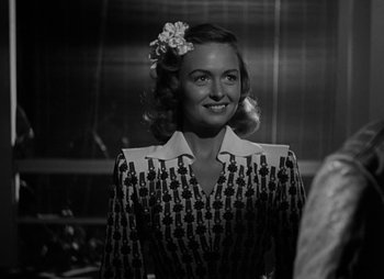 Movie still from “They Were Expendable” (1945), directed by Robert Montgomery – A black and white photo of a woman with a flower in her hair; Medium shot, Over the shoulder angle