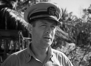 Movie still from “They Were Expendable” (1945), directed by Robert Montgomery – A man wearing a hat standing in front of trees; Close Up shot, Low angle