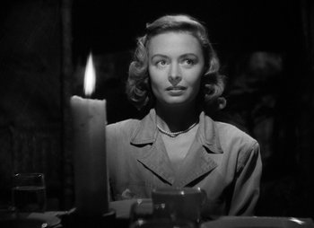 Movie still from “They Were Expendable” (1945), directed by Robert Montgomery – A black and white photo of a woman sitting in front of a lit candle; Close Up shot, Over the shoulder angle