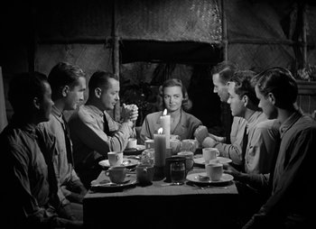 Movie still from “They Were Expendable” (1945), directed by Robert Montgomery – A group of people sitting around a table with a candle; Medium shot, High angle
