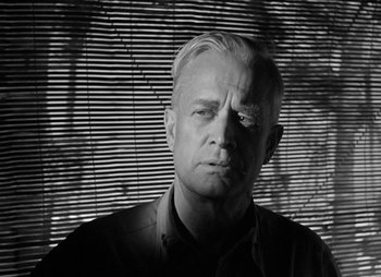 Movie still from “They Were Expendable” (1945), directed by Robert Montgomery – Black and white photograph of a man in front of a window; Close Up shot, Low angle