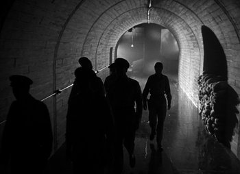 Movie still from “They Were Expendable” (1945), directed by Robert Montgomery – A group of people walking down a tunnel; Wide shot, Low angle