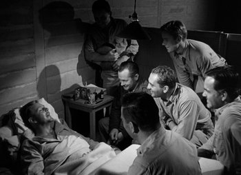 Movie still from “They Were Expendable” (1945), directed by Robert Montgomery – A black and white photo of a group of men sitting in a room; Wide shot, High angle