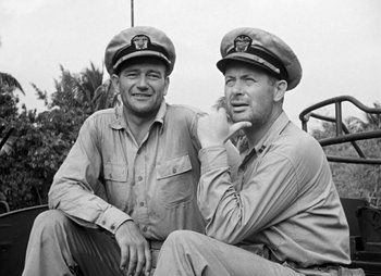 Movie still from “They Were Expendable” (1945), directed by Robert Montgomery – A couple of men sitting next to each other on a bench; Medium shot, Low angle