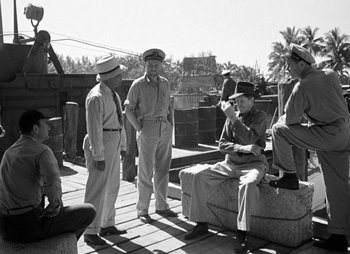 Movie still from “They Were Expendable” (1945), directed by Robert Montgomery – A black and white photo of a group of men in uniform; Wide shot, Over the shoulder angle
