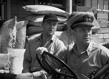 Movie still from “They Were Expendable” (1945), directed by Robert Montgomery – A black and white photo of two men sitting next to each other; Medium shot, Low angle