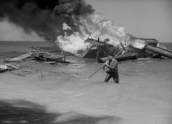 Movie still from “They Were Expendable” (1945), directed by Robert Montgomery – A man holding a stick while standing in the water; Wide shot, High angle