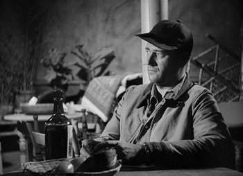 Movie still from “They Were Expendable” (1945), directed by Robert Montgomery – A black and white photo of a man sitting at a table; Medium shot, Low angle