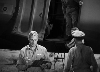 Movie still from “They Were Expendable” (1945), directed by Robert Montgomery – A man in an army uniform writing on a clipboard; Medium shot, High angle
