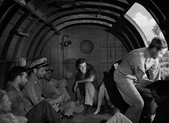 Movie still from “They Were Expendable” (1945), directed by Robert Montgomery – A black and white photo of a group of men sitting in a boat; Wide shot, High angle
