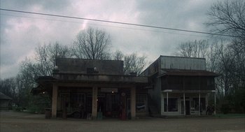 Movie still from “Thieves Like Us” (1974), directed by Robert Altman – An old store and a building on a dirt road; Extreme Wide shot, Low angle