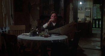 Movie still from “Thieves Like Us” (1974), directed by Robert Altman – A man sitting at a table drinking a beverage; Medium shot, Low angle
