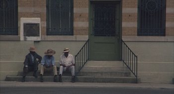 Movie still from “Thieves Like Us” (1974), directed by Robert Altman – A couple of men sitting on steps next to each other; Wide shot, High angle