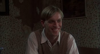 Movie still from “Thieves Like Us” (1974), directed by Robert Altman – A young man smiles while sitting in a room; Close Up shot, Low angle