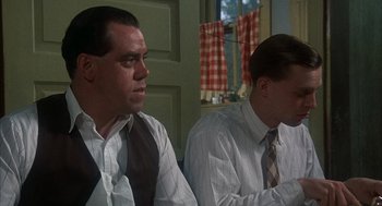Movie still from “Thieves Like Us” (1974), directed by Robert Altman – A couple of men sitting next to each other in front of a window; Medium shot, Low angle