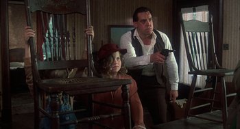 Movie still from “Thieves Like Us” (1974), directed by Robert Altman – A man and a woman sitting at a table holding guns; Medium shot, Low angle