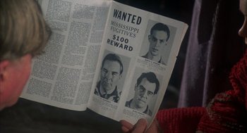Movie still from “Thieves Like Us” (1974), directed by Robert Altman – A person holding up a wanted poster with a picture of a man; Close Up shot, High angle
